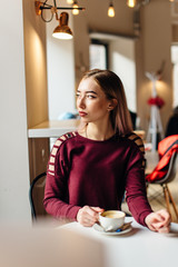 Young girl sit with cup of coffee and smile to the camera