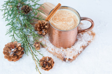 Eggnog in a copper mug with snow seasonal decorations