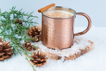 Obraz na płótnie Canvas Eggnog in a copper mug with snow seasonal decorations