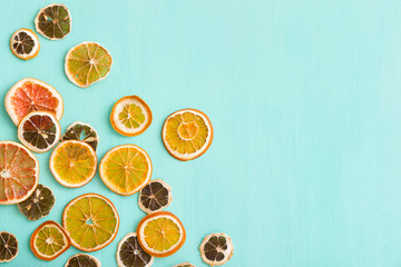 Top view on handmade citrus chips: orange, lemon, grapefruit on turquoise wooden background.