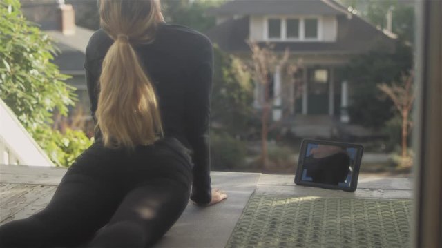 Young athletic woman doing doing yoga on her house porch.