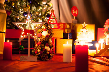 Christmas star in front of Christmas tree with garlands and decoration in the house. Decorative and festive green tree