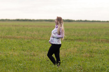 Pregnant girl walking in nature and smiling