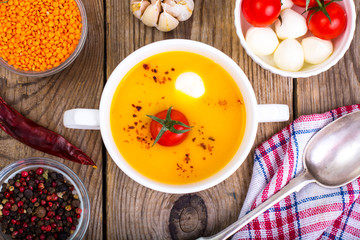 White bowl with cream soup of lentils, tomatoes and mozzarella