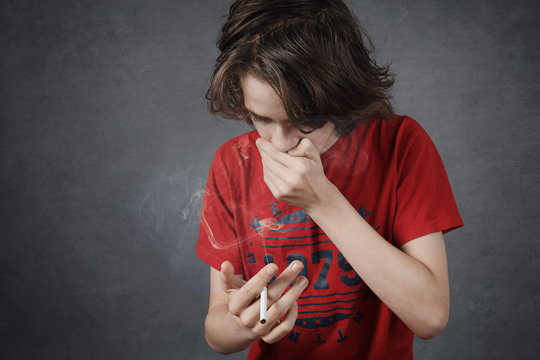 jeune adolescent gar&ccedil;on d&eacute;go&ucirc;t&eacute; par sa premi&egrave;re cigarette