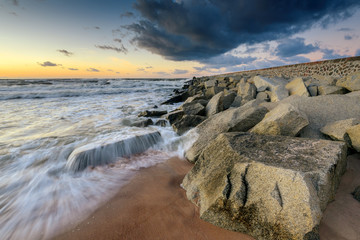 Stone breakwater in the Baltic Sea at sunset. Poland.