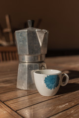 Italian "moka" coffee maker with small cup on rustic wooden background.
