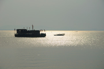 A silhouette of a tourist boat and fishing boat on the waters of Tai Lake, Taihu outside of the three kingdoms city scenic area in Wuxi China in Jiangsu province as the sun sets.