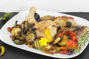 Un plato con muslos de pollo, asados con vegetales y pimientos de chile