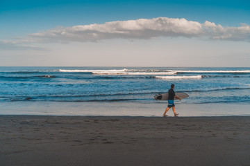 Fototapeta na wymiar Surfer with his surfboard walking along the cuta beach, Bali