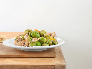 Plate with yummy brussel sprouts salad on wooden table against light background