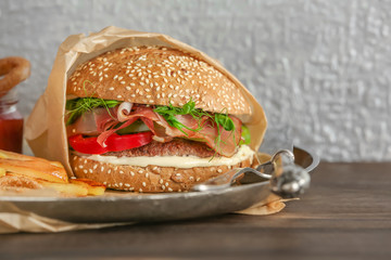 Tasty burger with prosciutto on table
