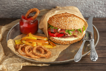 Tasty burger with prosciutto on table