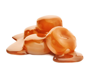 Delicious candies with caramel sauce on white background