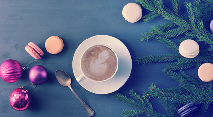 Christmas background - Cup of cappuccino with cake, macarons, Christmas toys and tree branches