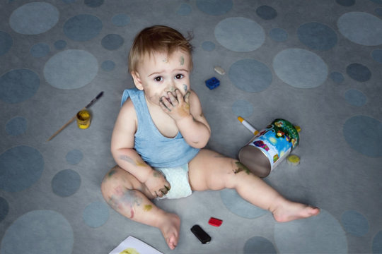 Cute little boy sitting on the floor and painting