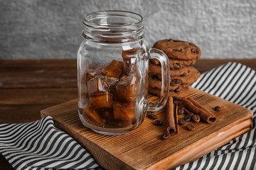 Mason jar with frozen coffee cubes on wooden board