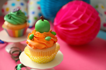 Stand with tasty bright cupcake on color background