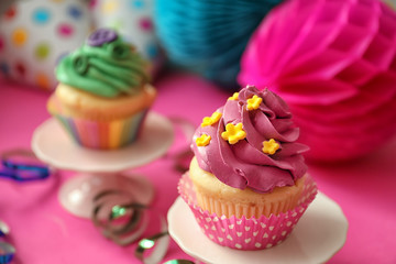 Stand with tasty bright cupcake on color background