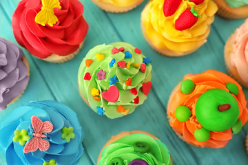 Tasty colorful cupcakes on wooden background
