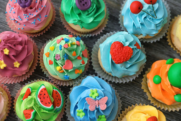 Tasty colorful cupcakes on wooden background