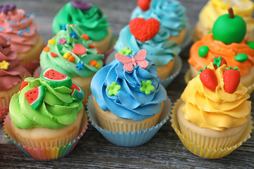Tasty colorful cupcakes on wooden background