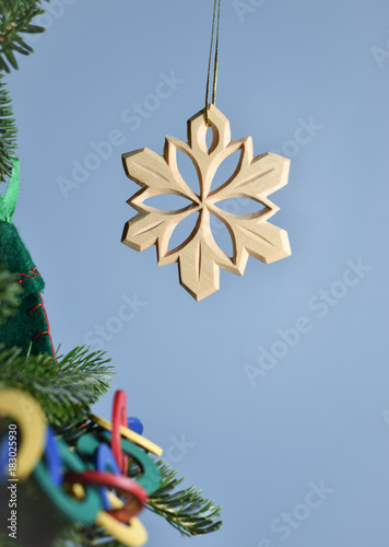 Hand Carved Wooden Snow Flake Ornament Hanging At Edge Of A Hand Carved Wooden Snow Flake Ornament Hanging At Edge Of A Decorated Tree