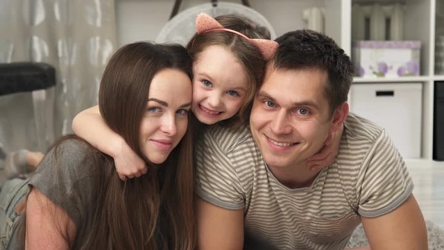 Close-up of a mother, father and little daughter smiling