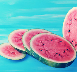 green watermelon cut into round slices on a blue  background