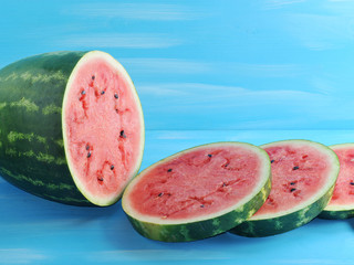 green watermelon cut into round slices on a blue  background