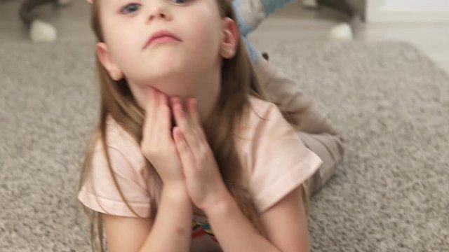 Cute little girl grimacing and smiling while lying on the floor