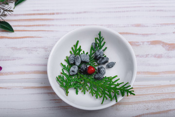 Twig sprig in a white plate on the table with New Year's decor