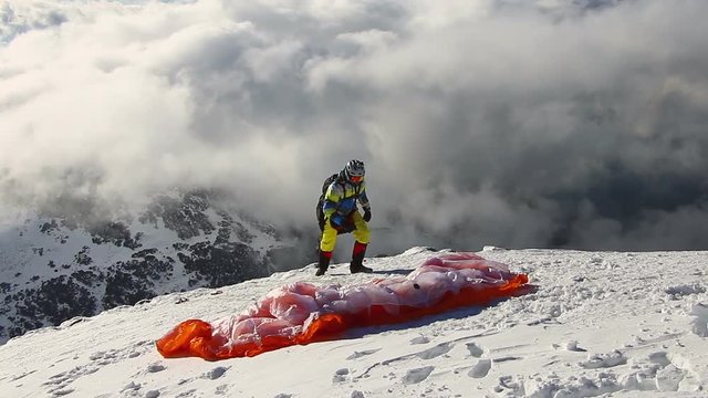 Paragliding above mountain peaks and clouds during winter sunny snowy day