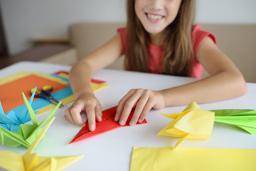 The girl puts origami from paper. Lesson of origami