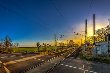 Beautiful blue and yellow sunset on level crossing, double track with passing train
