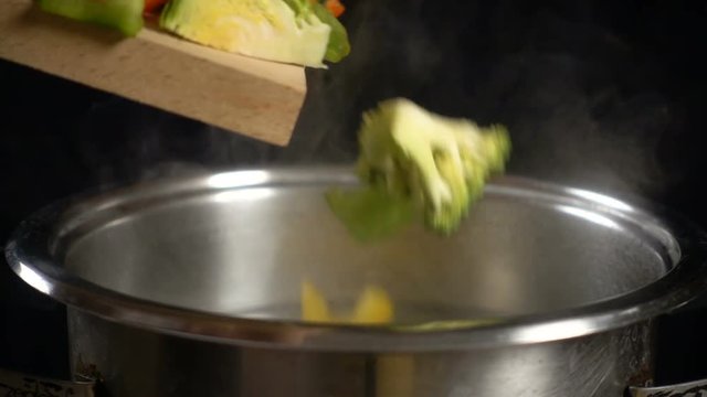 Adding a vegetables to boiling water in pan, slow motion