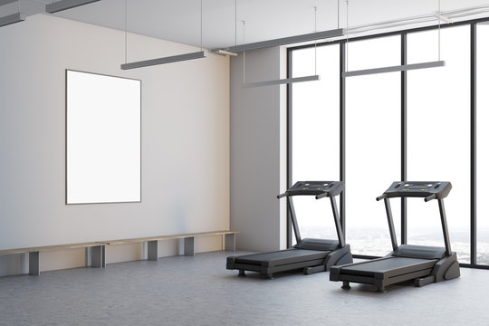 Two treadmills in a white room, side view