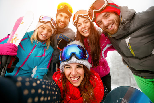 happy friends having fun on winter hodays. Snowbarders and skiers group team making selfie