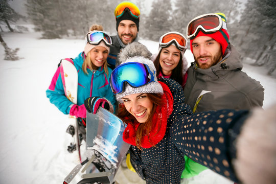 smiling friends having fun on winter hodays. Snowbarders and skiers group team making selfie