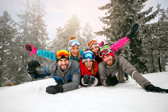 friends on winter holidays - Skiers lying on snow and having fun