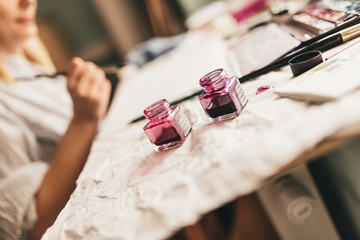 Beautiful blonde woman artist drawing with a brush and pain in her art studio