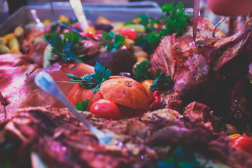 Big giant dish plate with roasted full pig pork head, served in restaurant with variety of vegetables and different meat assortment - lamb, ham and chicken.