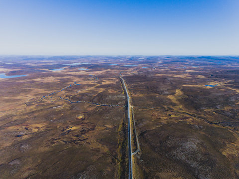 View of norwegian road through tundra valley, road in the middle of nowhere with empty landscape around, on the way to Nordkapp, Finnmark County, Norway, shot from drone