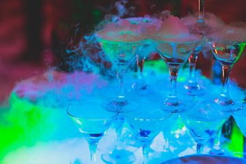 Beautiful pyramid line of different coloured alcohol cocktails with mint on christmas party, tequila, martini, vodka, and others on decorated catering bouquet table on