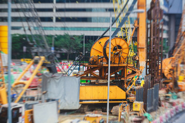 A large construction site in the city, the process of massive buliding construction with heavy vehicle at work, excavator, elevating crane and bulldozer