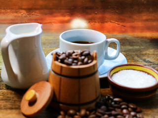 coffee in a white cup. grain coffee in a barrel. a jug of milk. sugar