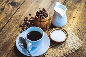 coffee in a white cup. grain coffee in a barrel. a jug of milk. sugar