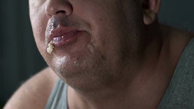 Closeup of fat mans face chewing oily food, lonely overweight person having meal