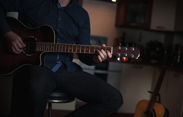 Fototapeta premium The Guitarist Guy plays the guitar in a bar in a beautiful setting on a high bar stool