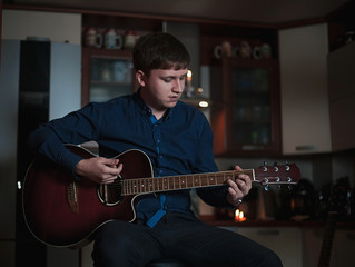 Obraz premium The Guitarist Guy plays the guitar in a bar in a beautiful setting on a high bar stool